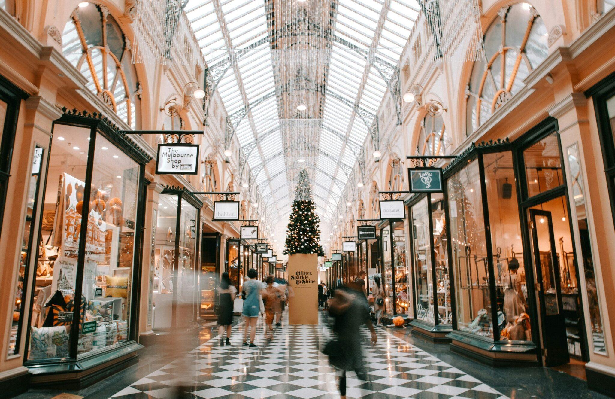 Galerie commerciale couverte ornée de décorations de Noël avec sapin illuminé au centre et boutiques élégantes