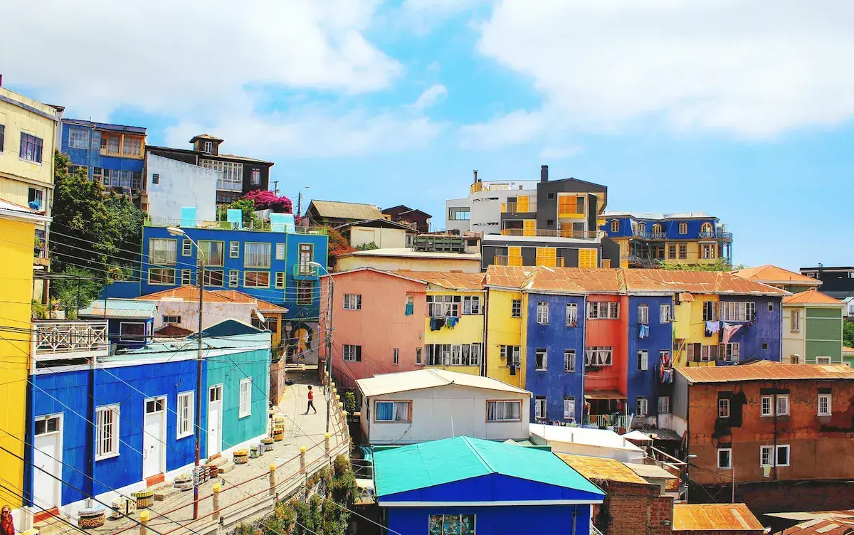 Des maisons colorées aux façades jaunes, bleues, rouges et roses sur les pentes d’une colline côtière