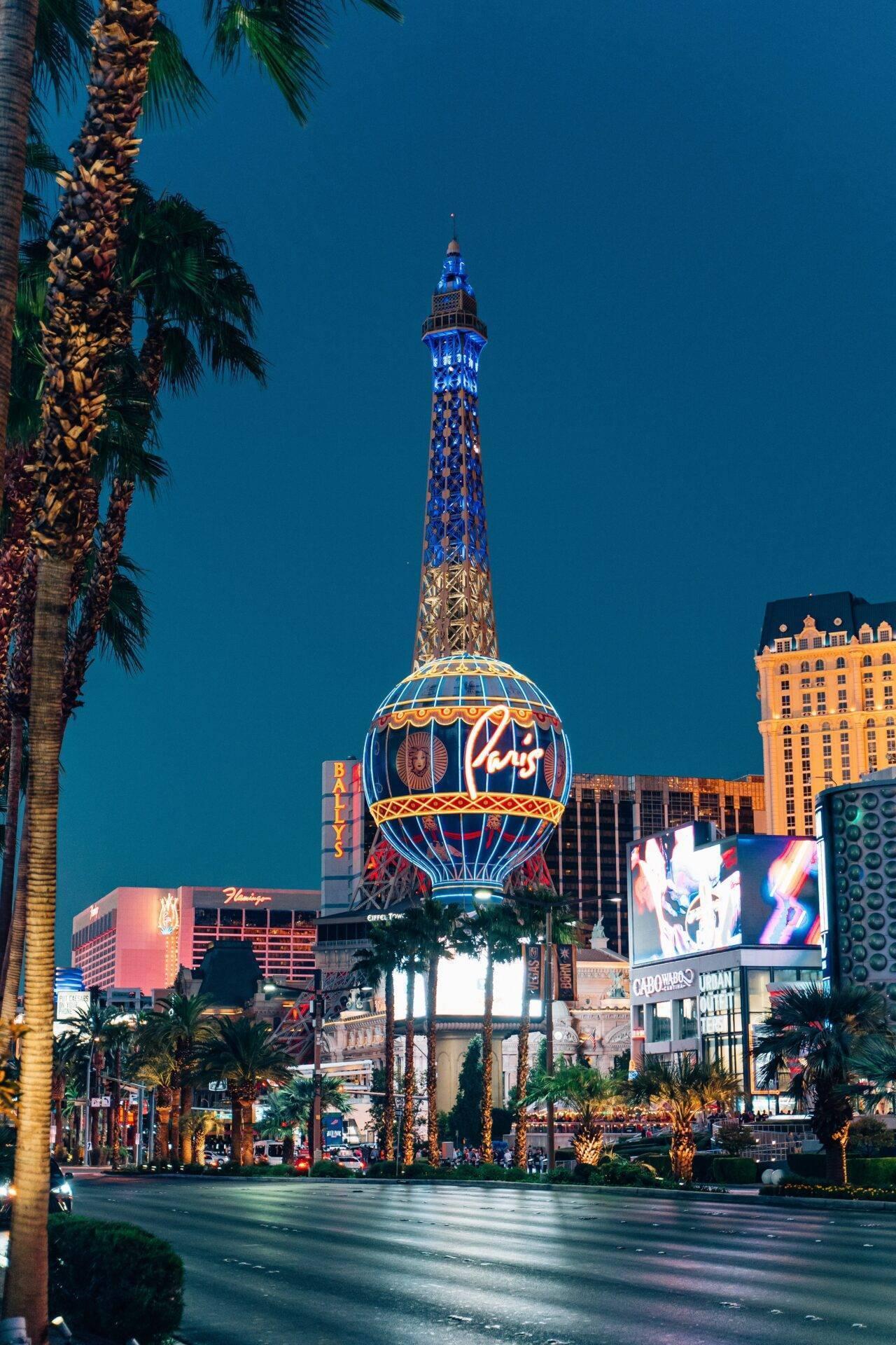 Vue nocturne d’une célèbre rue touristique avec tour illuminée en bleu et bâtiments casinos bordant l’avenue