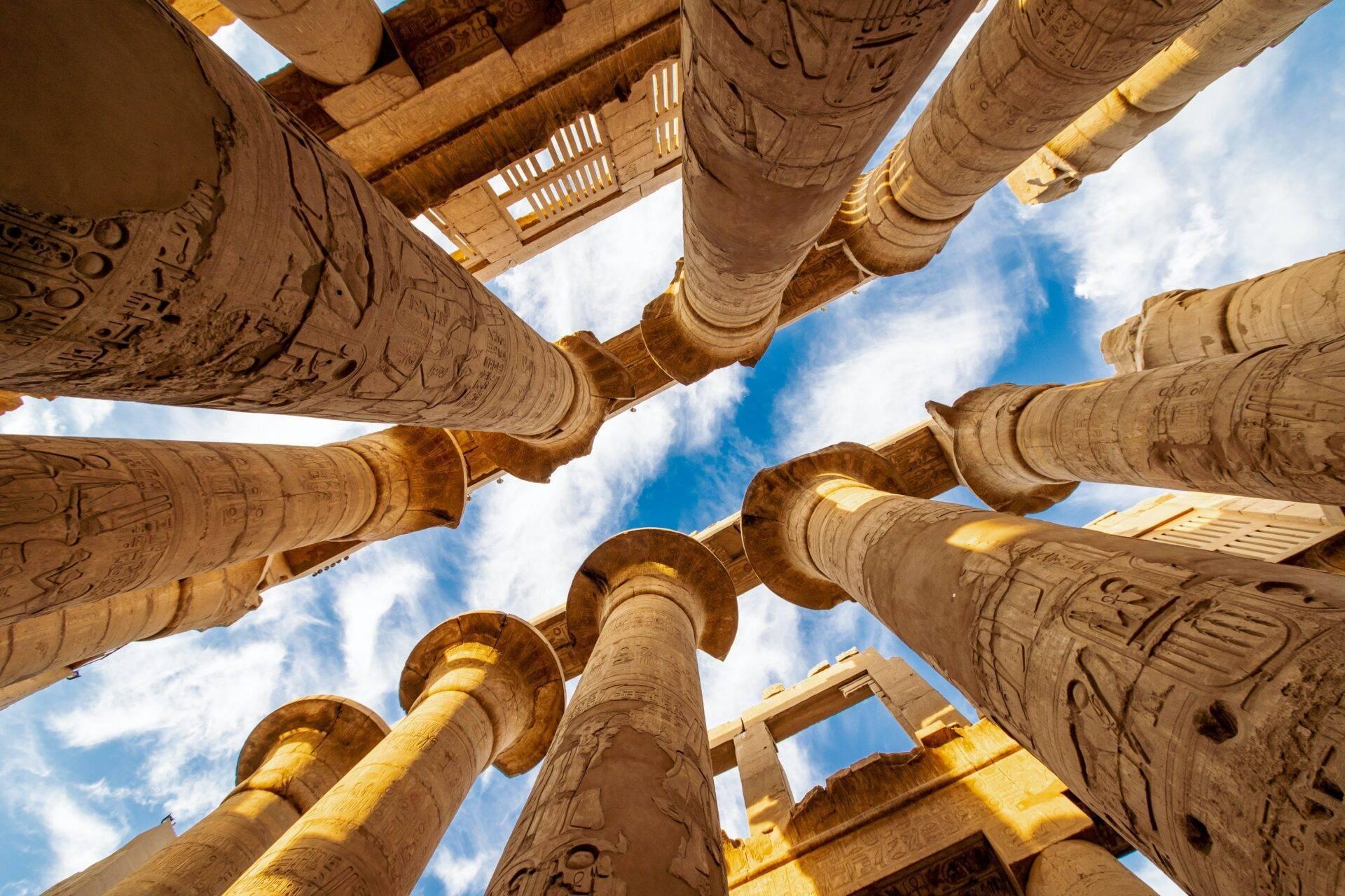 Vue de dessous de colonnes pharaoniques ornées de hiéroglyphes dans un temple égyptien ancien