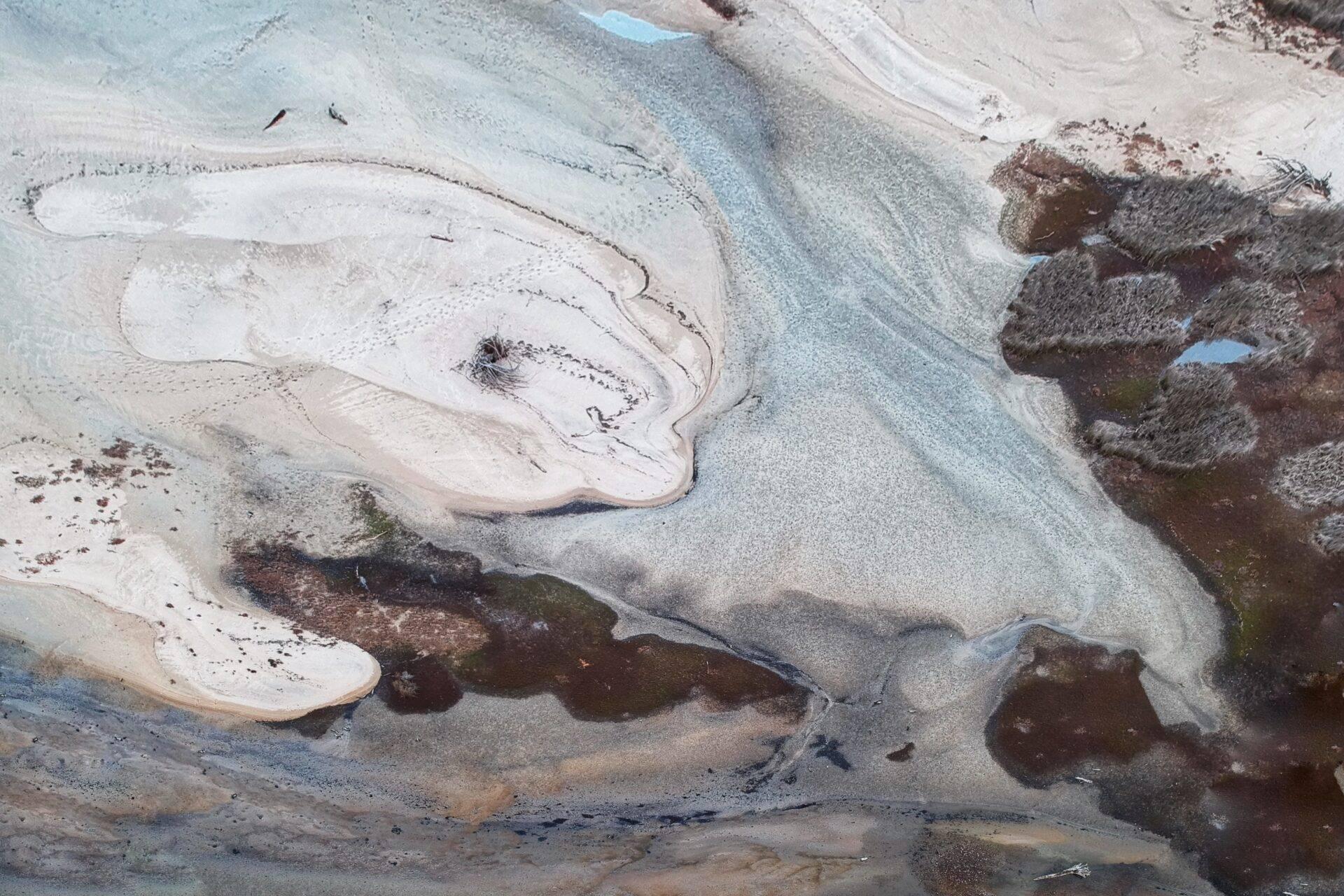 Vue aérienne de bassins géothermiques aux eaux turquoise entourés de formations minérales colorées en blanc et brun