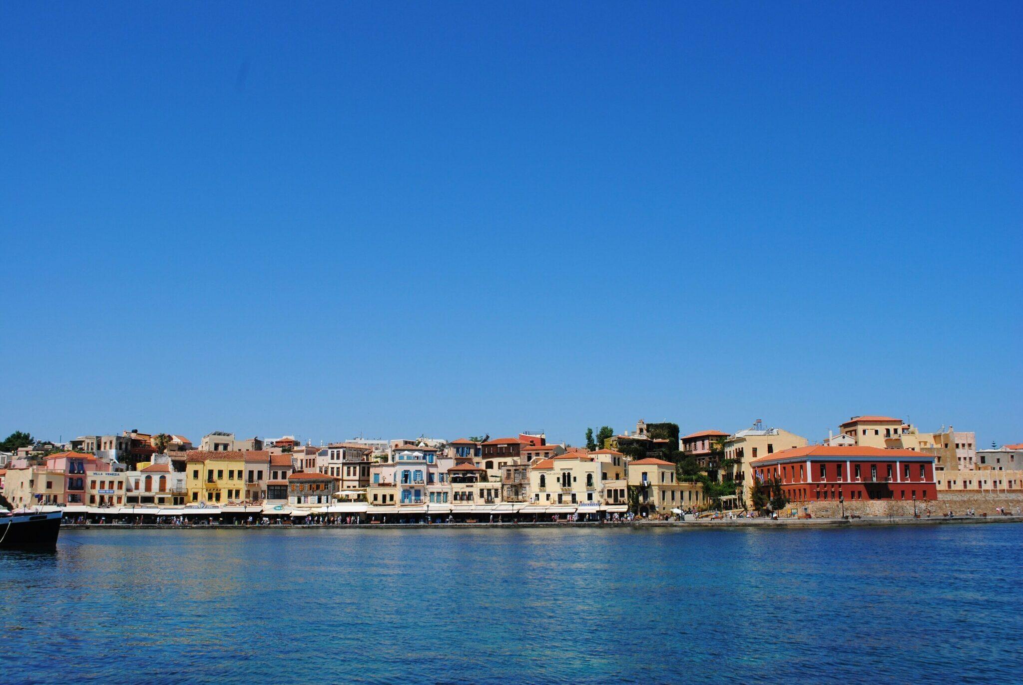 Façade colorée d’une ville portuaire méditerranéenne avec bâtiments traditionnels surplombant une mer turquoise