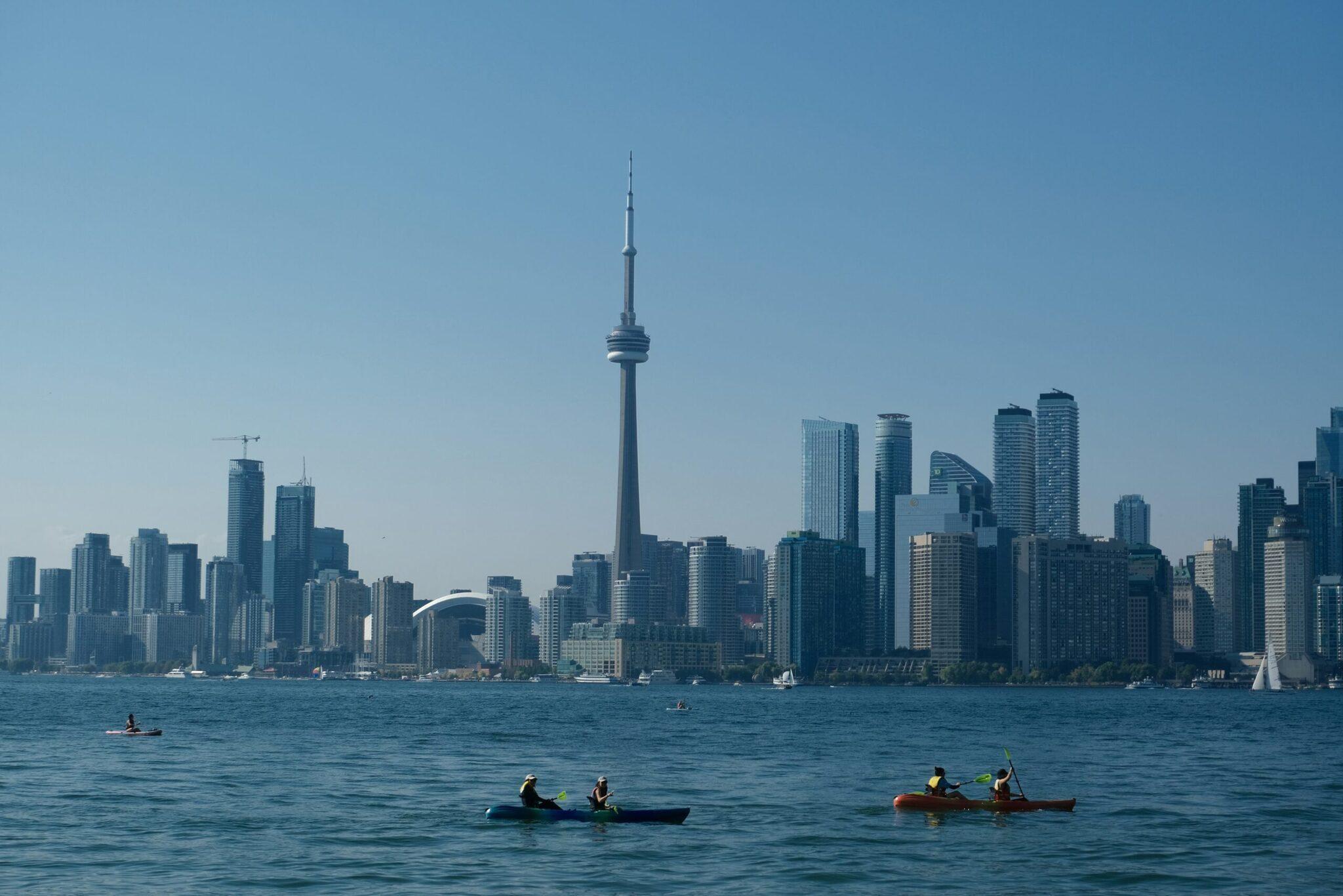 Vue panoramique d’un skyline urbain avec tour caractéristique depuis le lac, avec kayakistes au premier plan