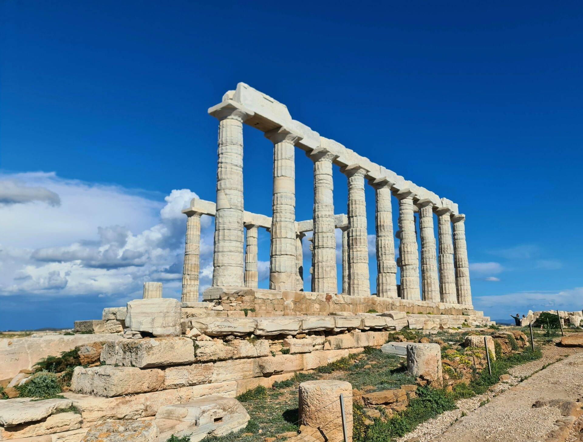 Ruines d’un temple antique avec colonnes doriques en pierre blanche sous un ciel bleu dégagé