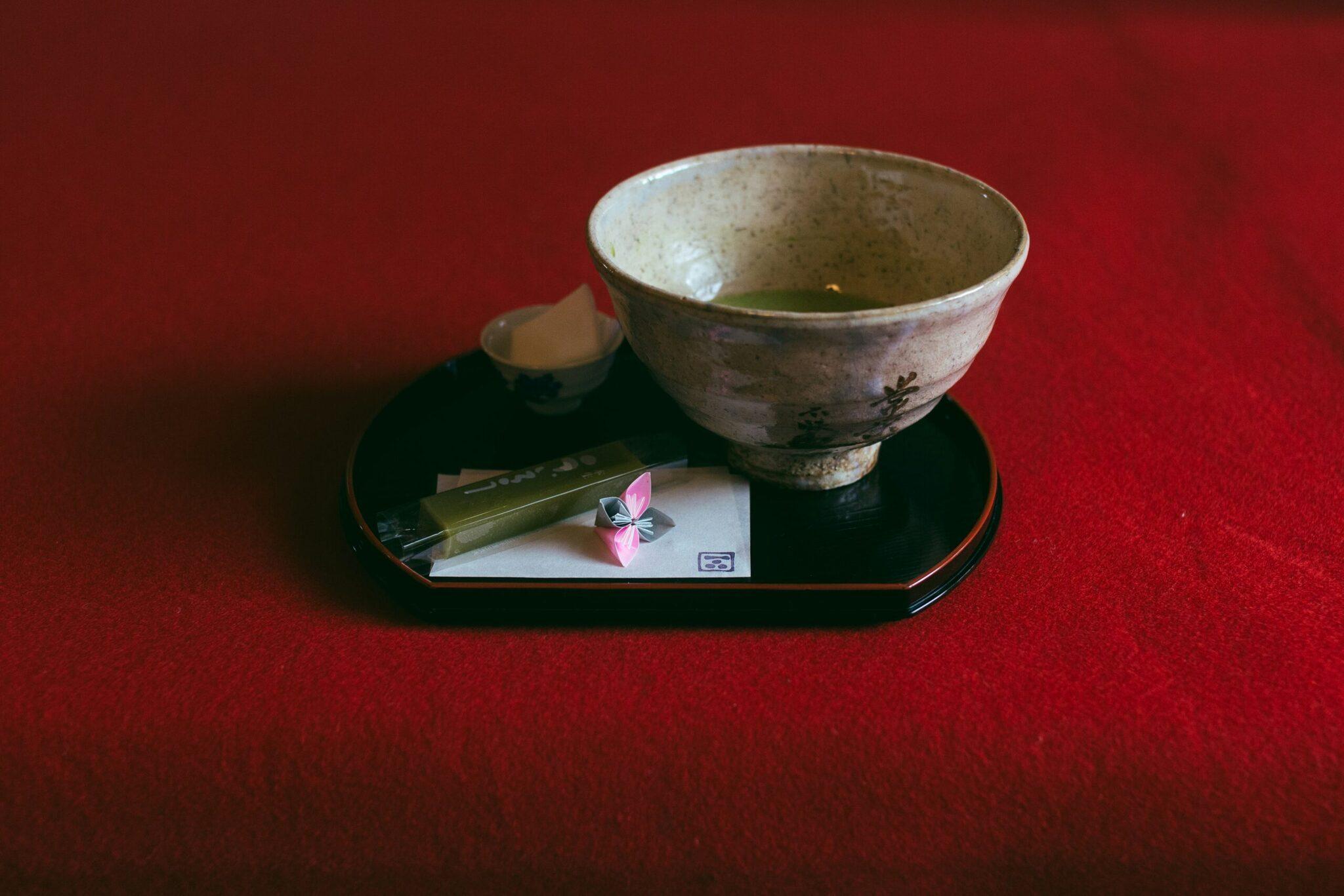 Un bol de thé matcha traditionnel présenté sur un plateau noir avec accessoires de cérémonie du thé japonaise