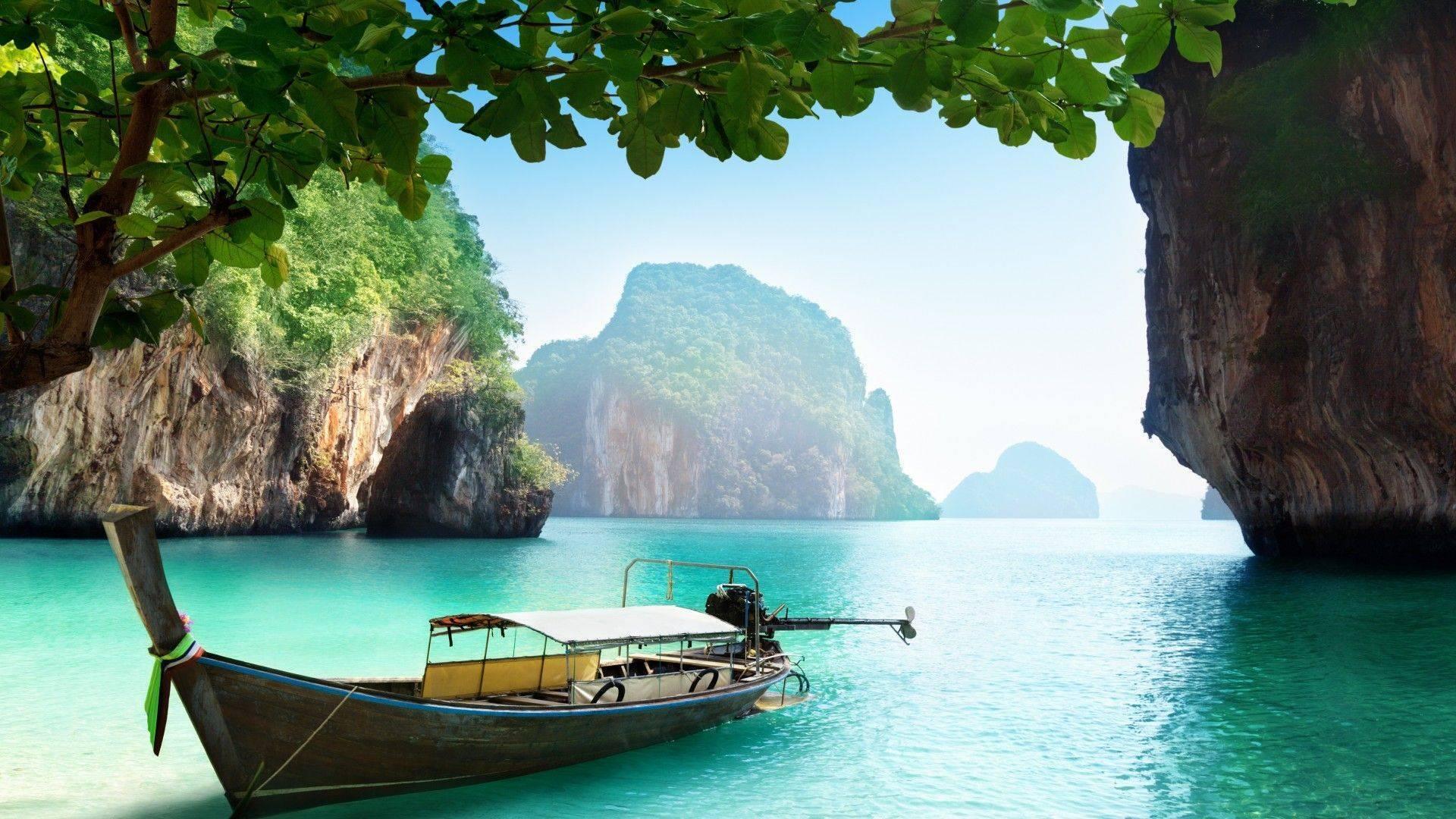 Un bateau traditionnel en bois amarré dans une baie turquoise entourée de falaises calcaires et de végétation tropicale