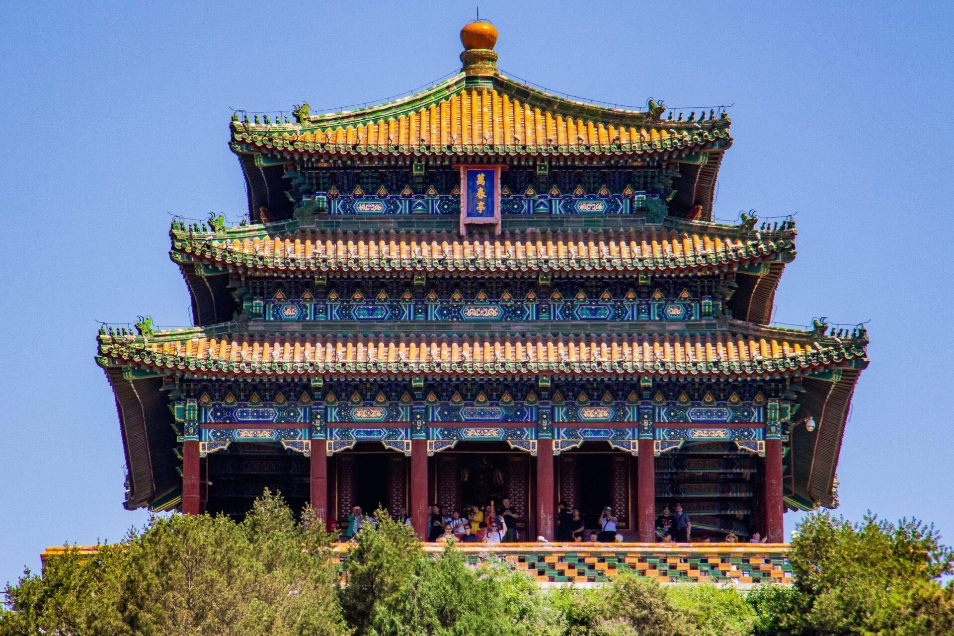 Un temple traditionnel chinois avec ses trois toits jaunes dorés superposés et ses colonnes rouges, sous un ciel bleu dégagé
