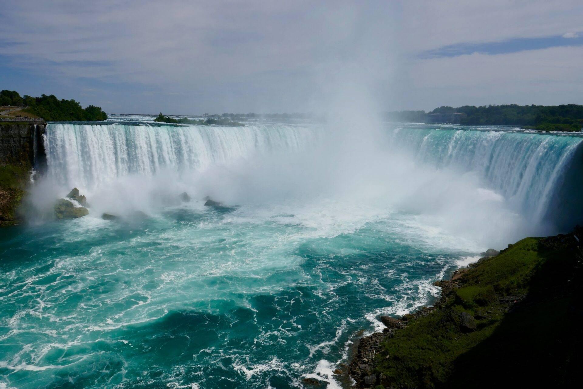 Imposantes chutes d’eau cascadant depuis des falaises rocheuses dans un brouillard blanc épais, avec des eaux turquoise tourbillonnantes en contrebas