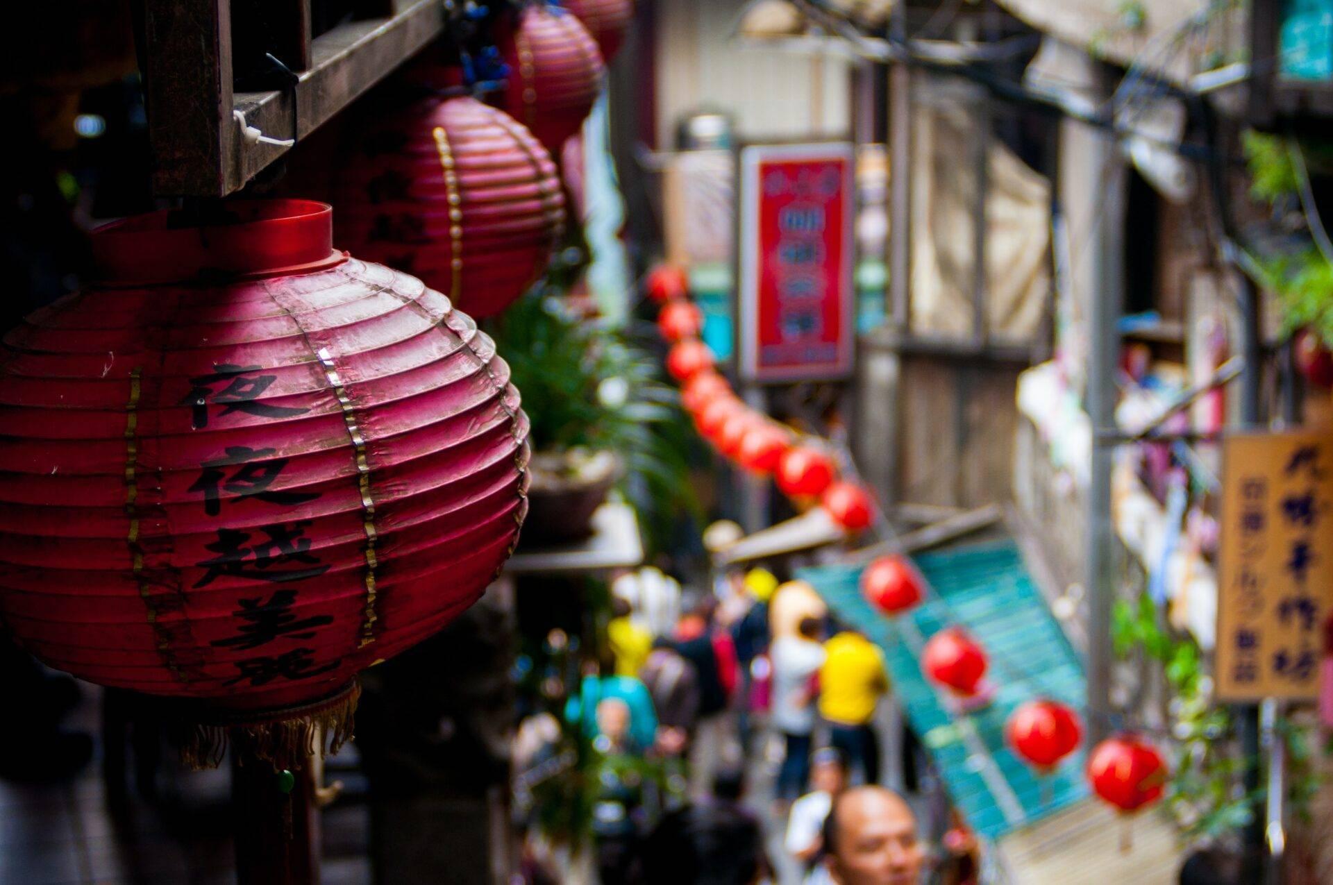 Lanternes rouges traditionnelles avec caractères chinois dans une ruelle animée d’une vieille ville asiatique