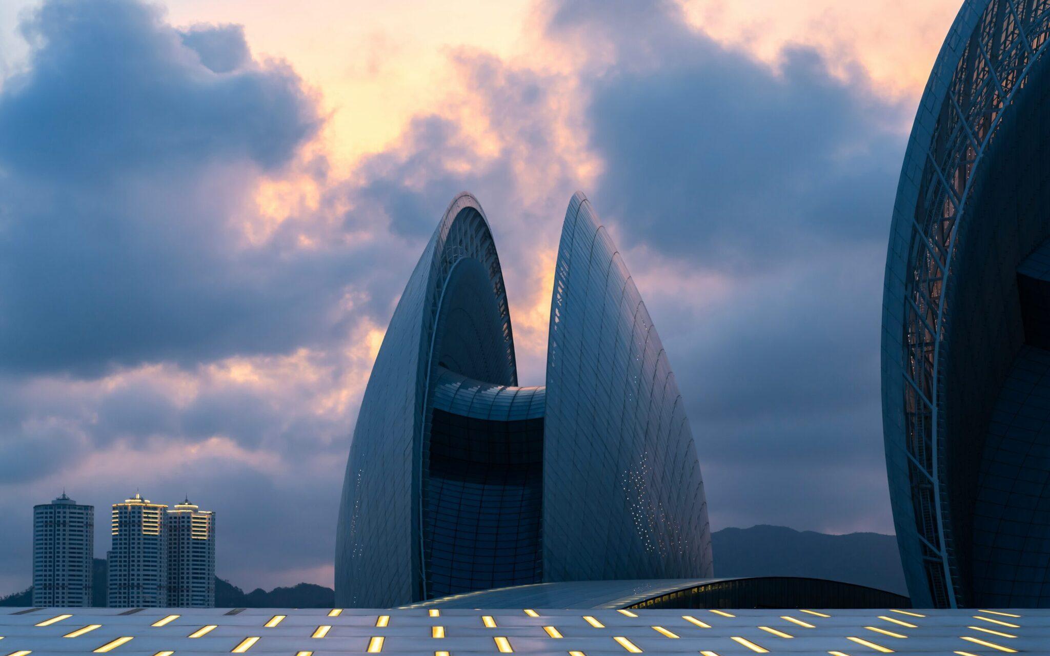 Architecture moderne futuriste avec bâtiments en forme de voile au coucher de soleil, entourée de gratte-ciel