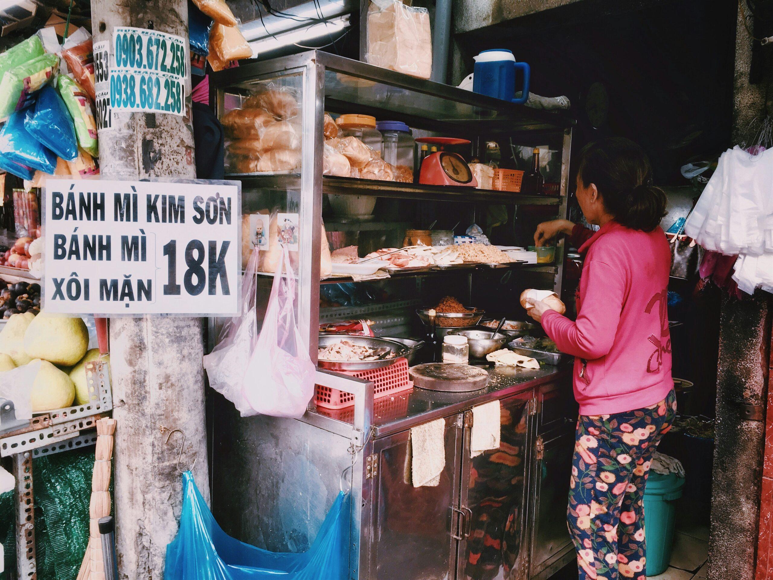 Une vendeuse de street food prépare des bánh mì dans une petite échoppe du Vieux Quartier de Hanoï