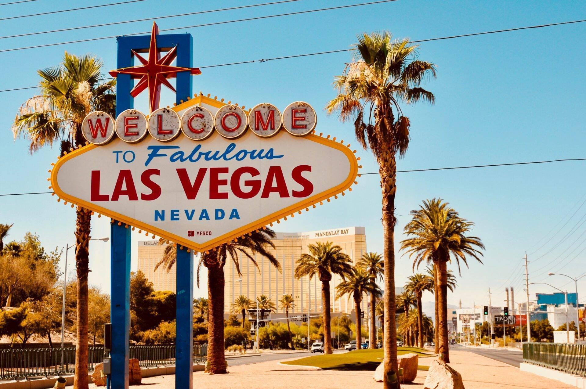 Le célèbre panneau de bienvenue à Las Vegas avec palmiers et casinos en arrière-plan sous un ciel bleu