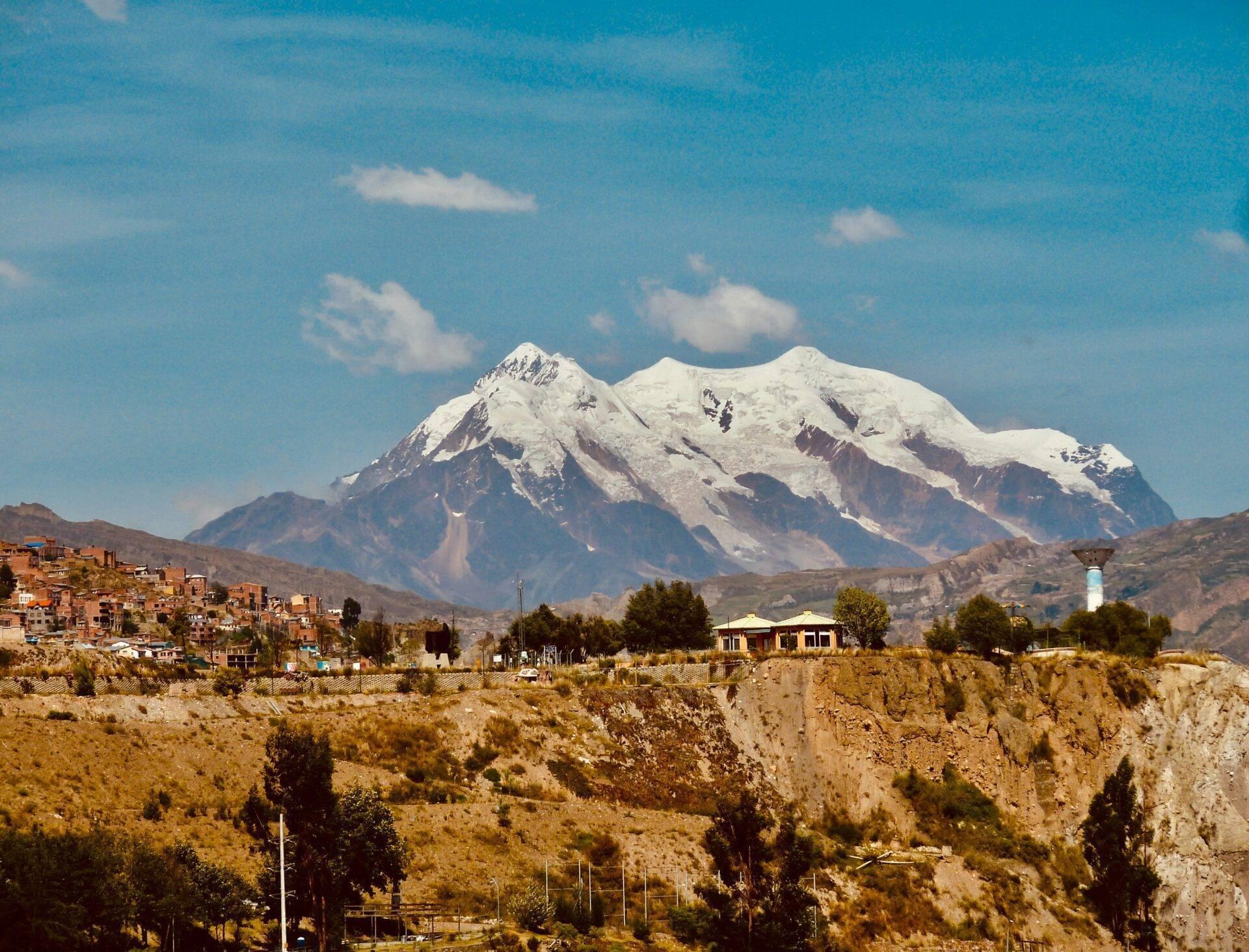 Ville de montagne andine avec maisons en adobe et volcan enneigé majestueux en arrière-plan sous ciel bleu