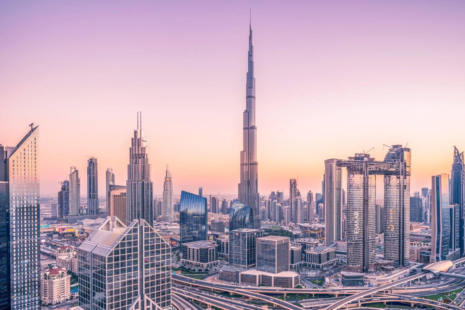 Skyline urbain densément construit avec gratte-ciel modernes et une tour emblématique centrale au coucher de soleil