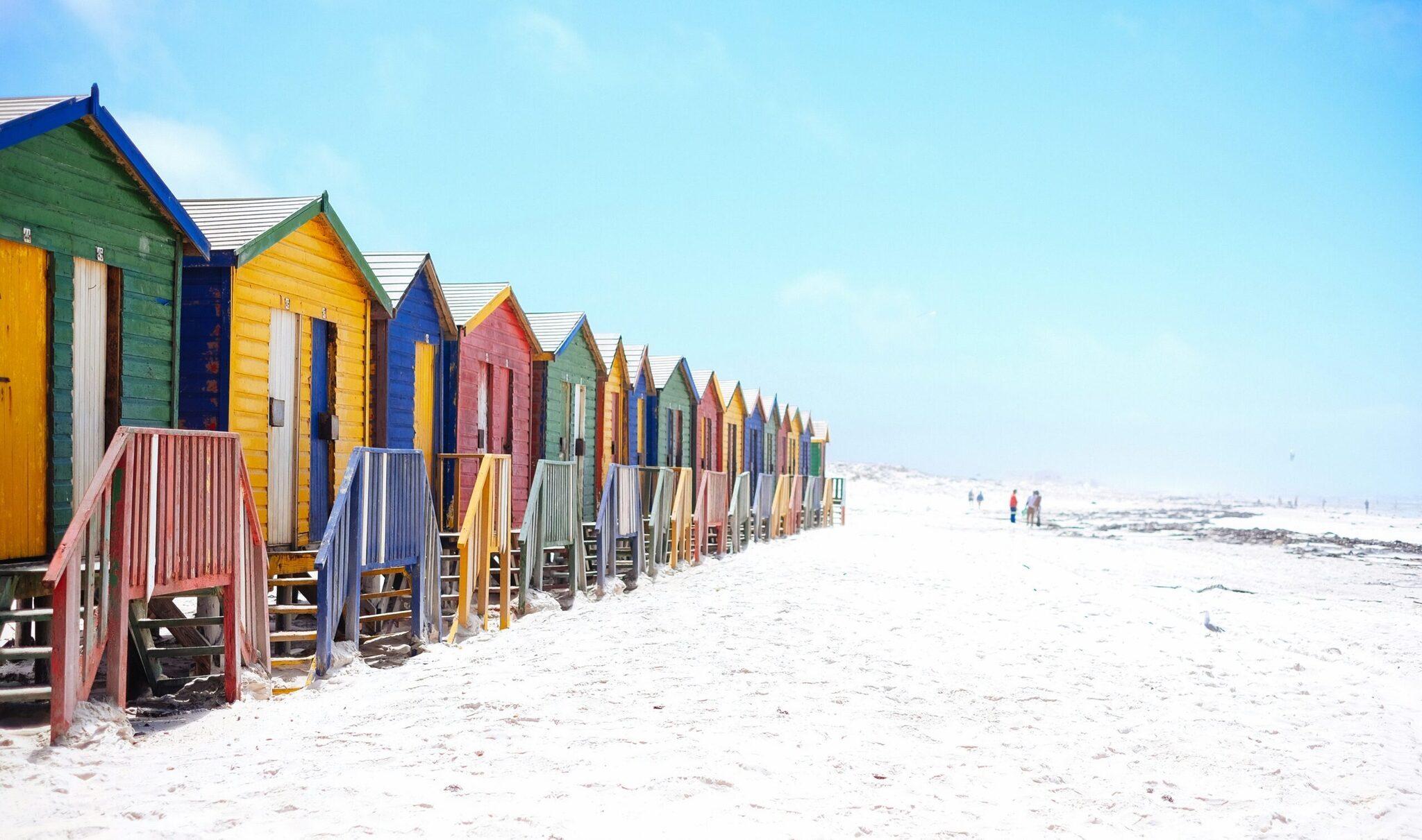 Rangée de cabines de plage colorées alignées sur le sable blanc d’une plage ensoleillée