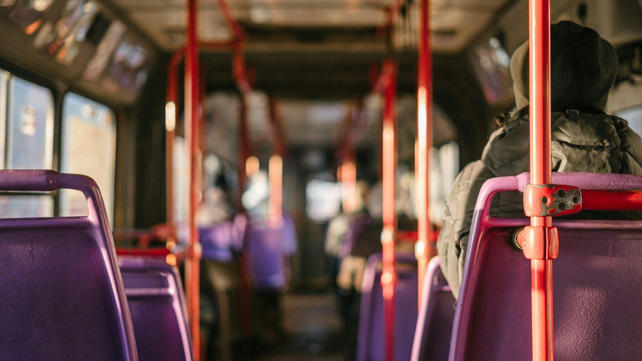 Intérieur d’un bus de transport en commun avec sièges violets et barres de maintien rouges
