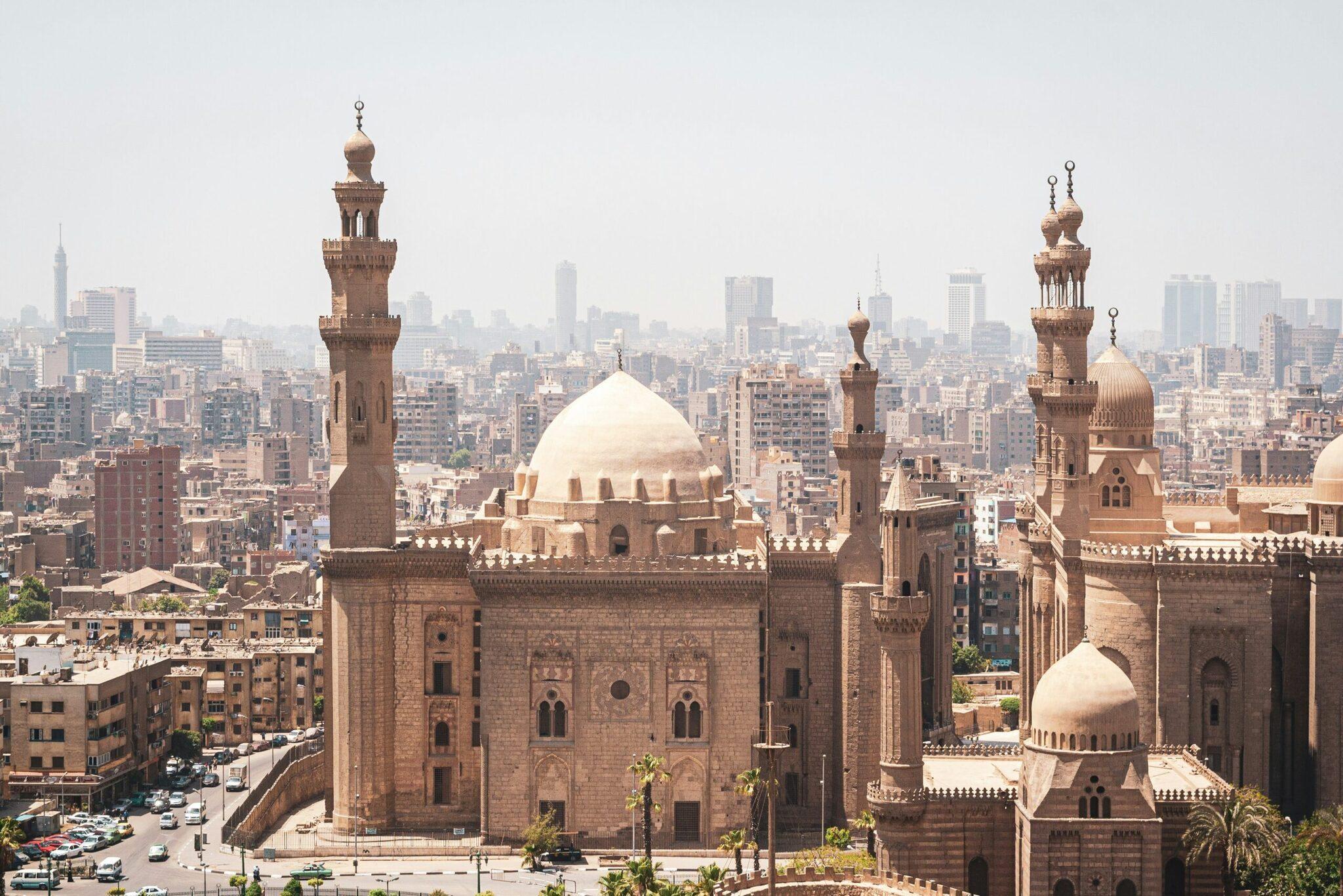 Vue panoramique du Caire avec mosquées historiques aux dômes blancs et minarets, dominant la skyline urbaine dense