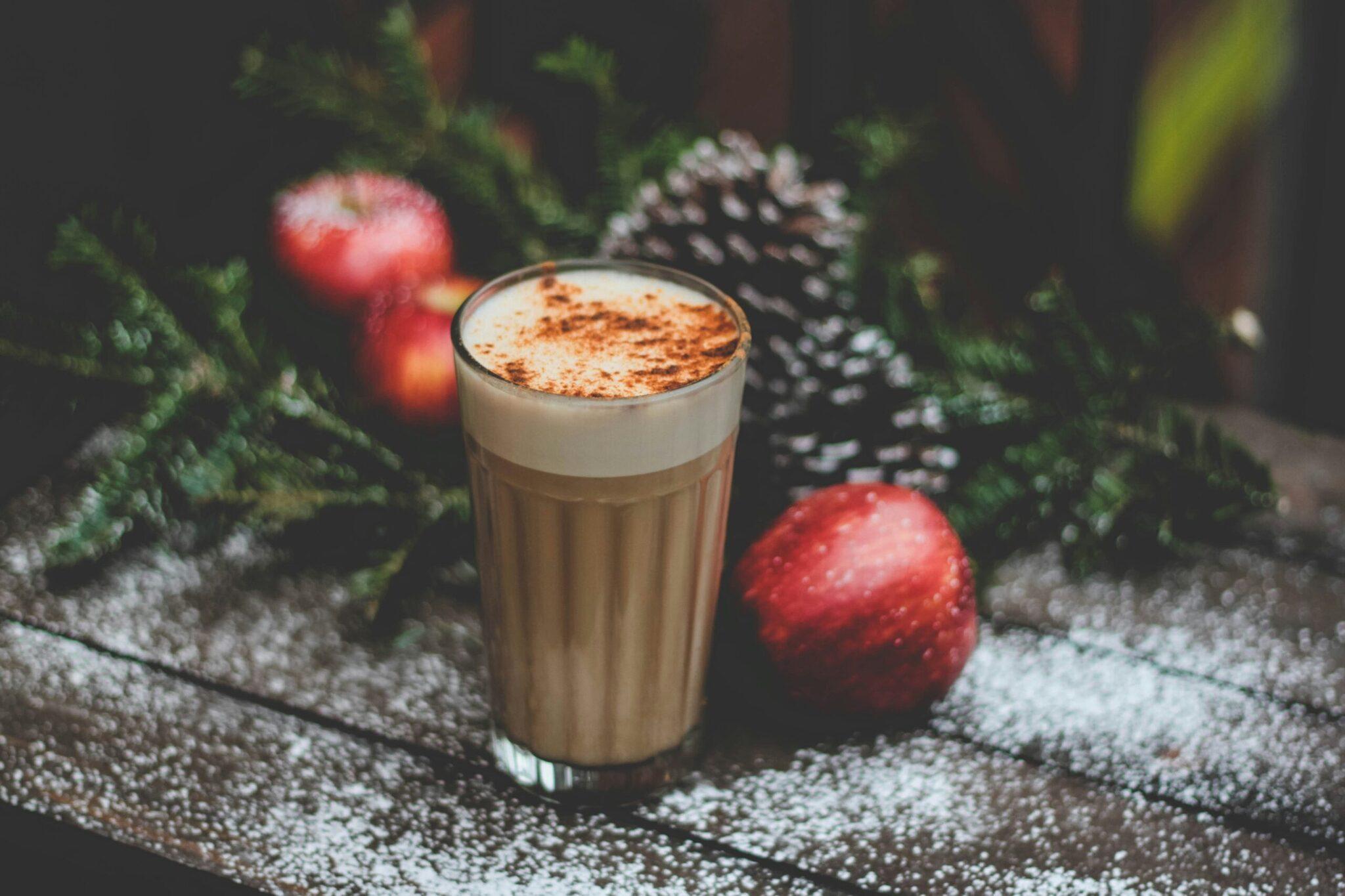Un café cappuccino garni de cacao sur une surface hivernale entourée de décorations de Noël