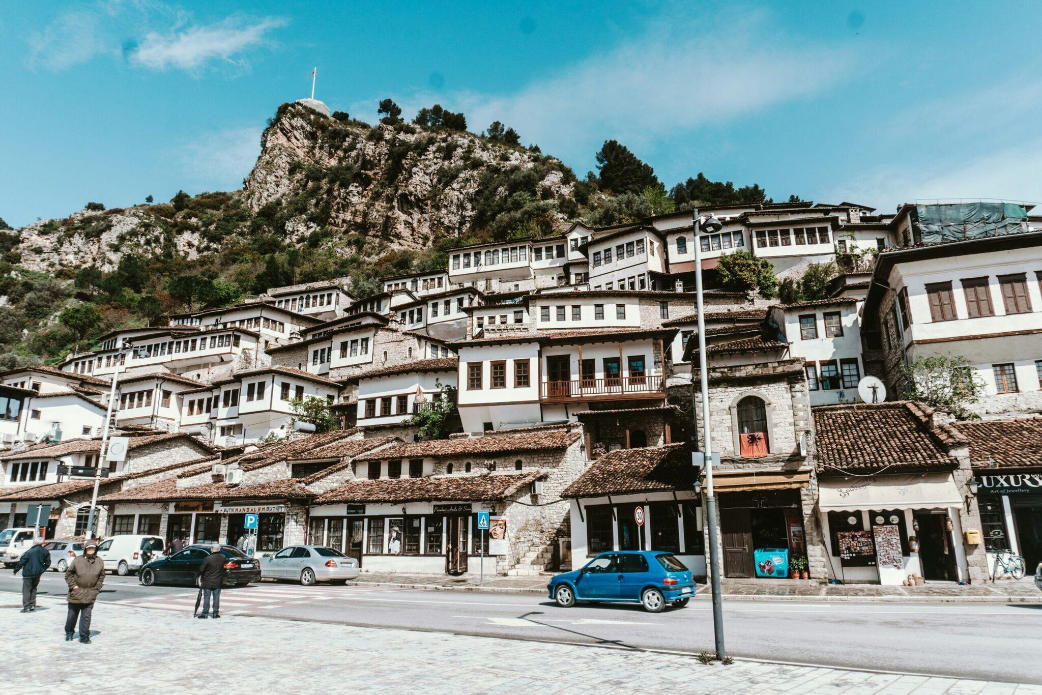 Une petite ville nichée au pied d’une montagne rocheuse avec maisons traditionnelles en pierre blanche et toits en tuiles