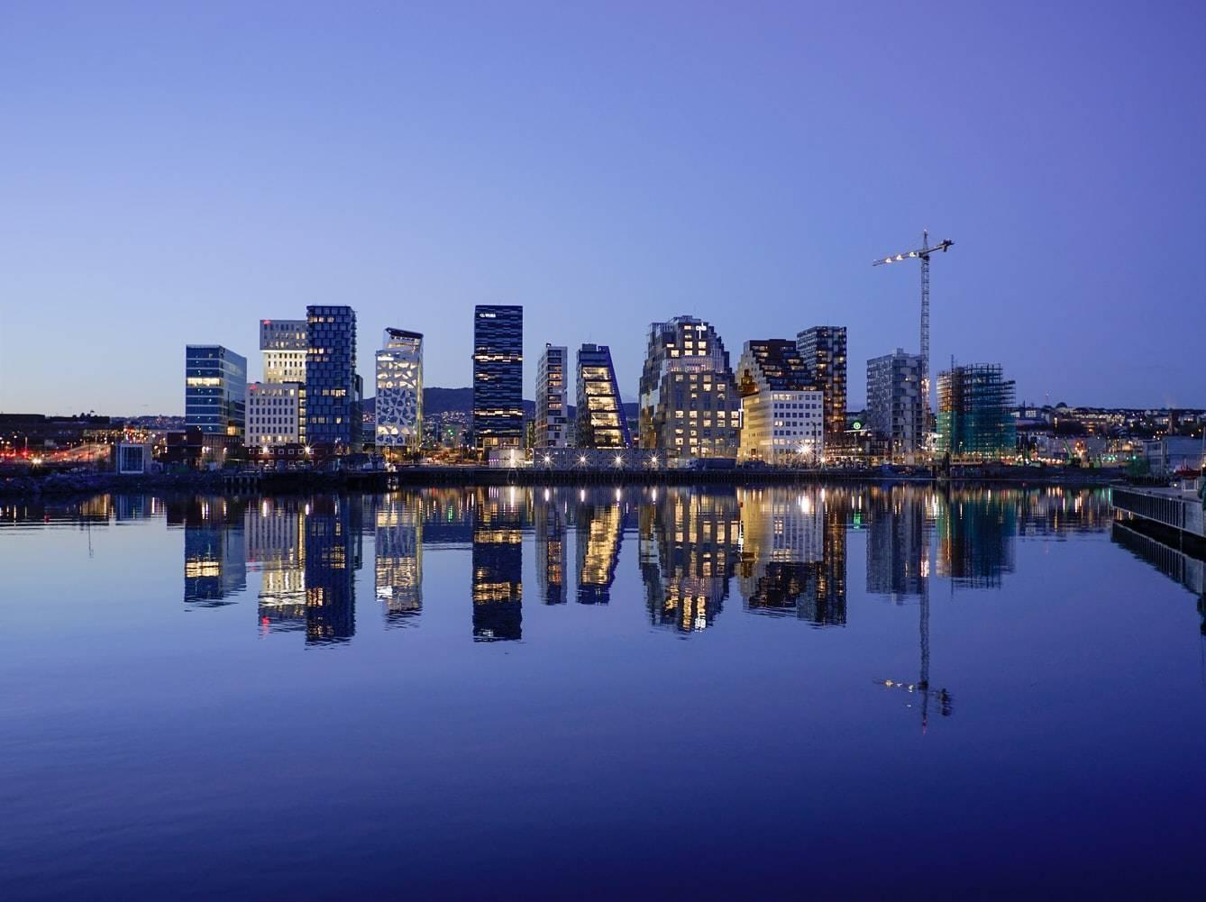 Skyline urbain illuminé la nuit se reflétant parfaitement dans l’eau calme d’une baie portuaire