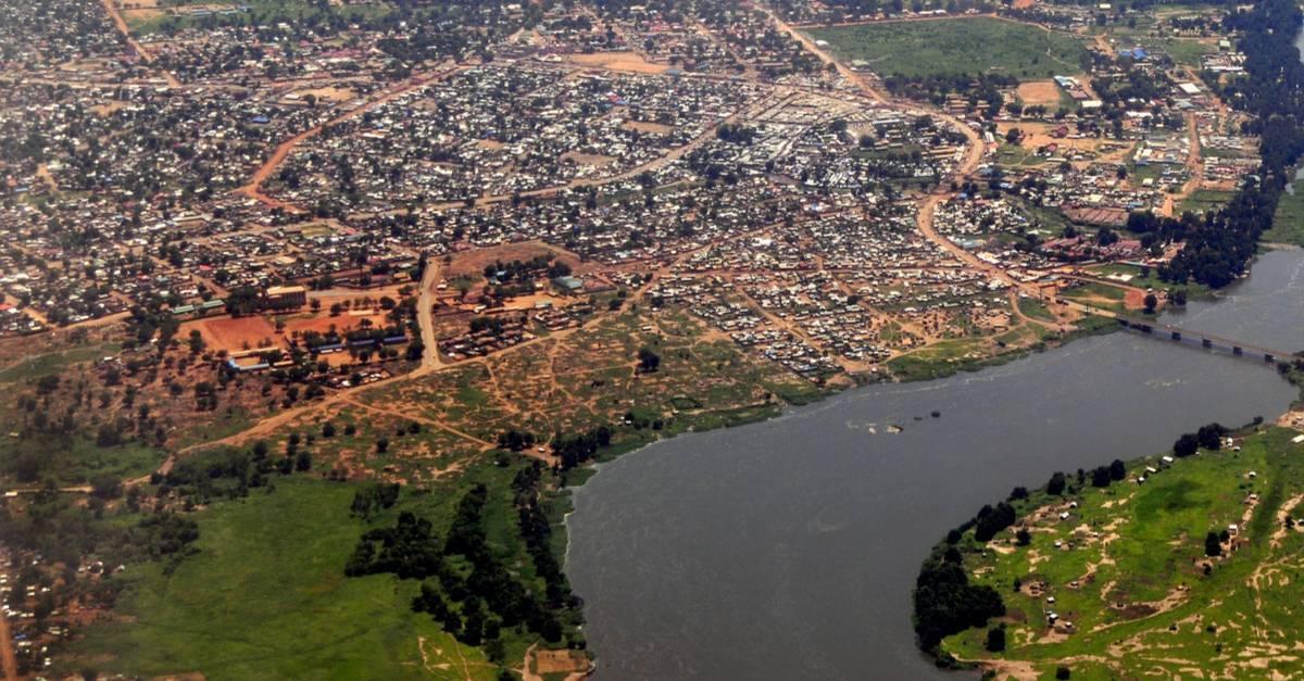 Vue aérienne d’une ville africaine avec rivière, habitat dispersé et terres rouges caractéristiques