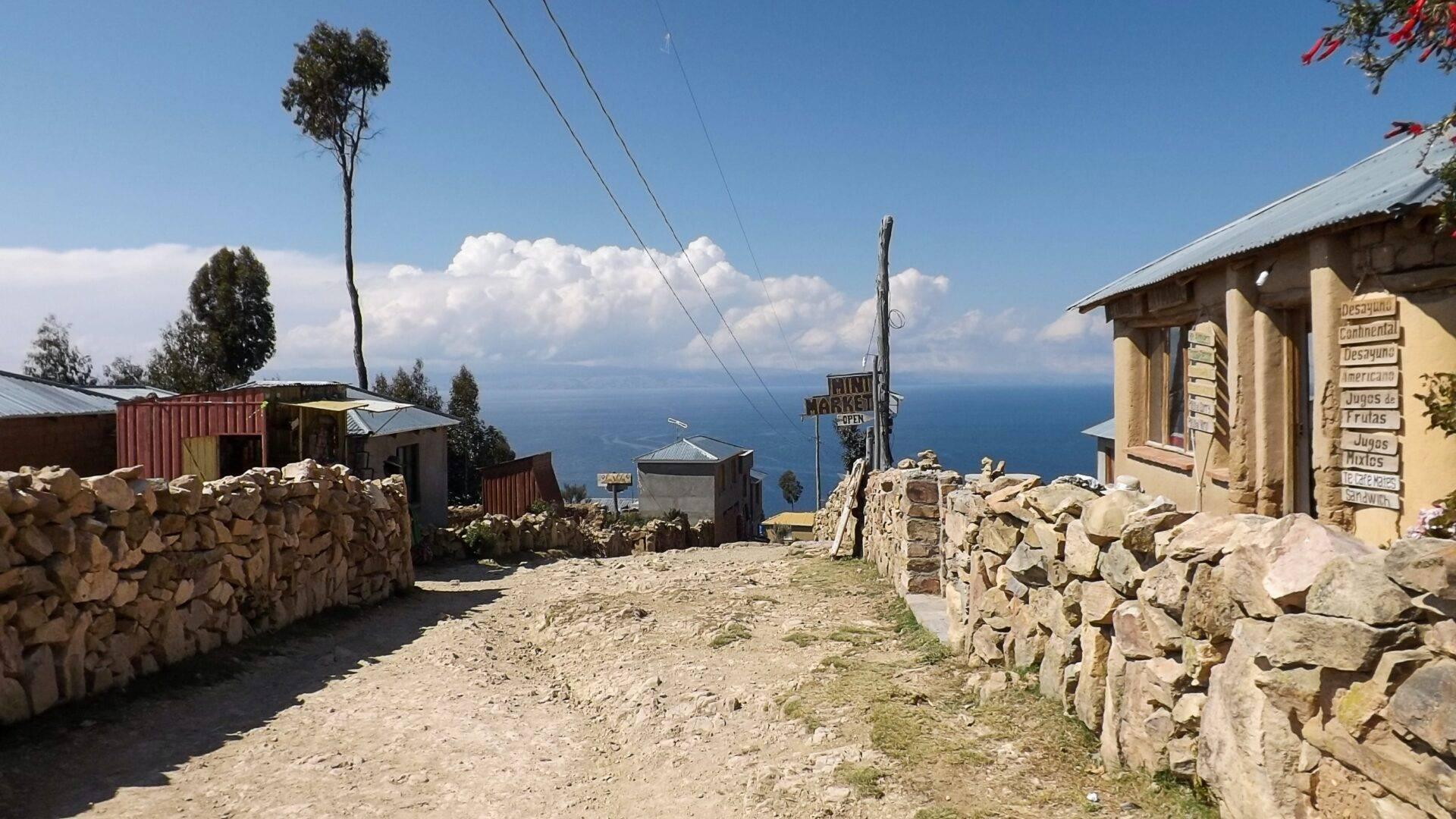 Un petit village de montagne en haute altitude avec des maisons en pierre, des murs de pierres sèches et une vue sur un lac en contrebas