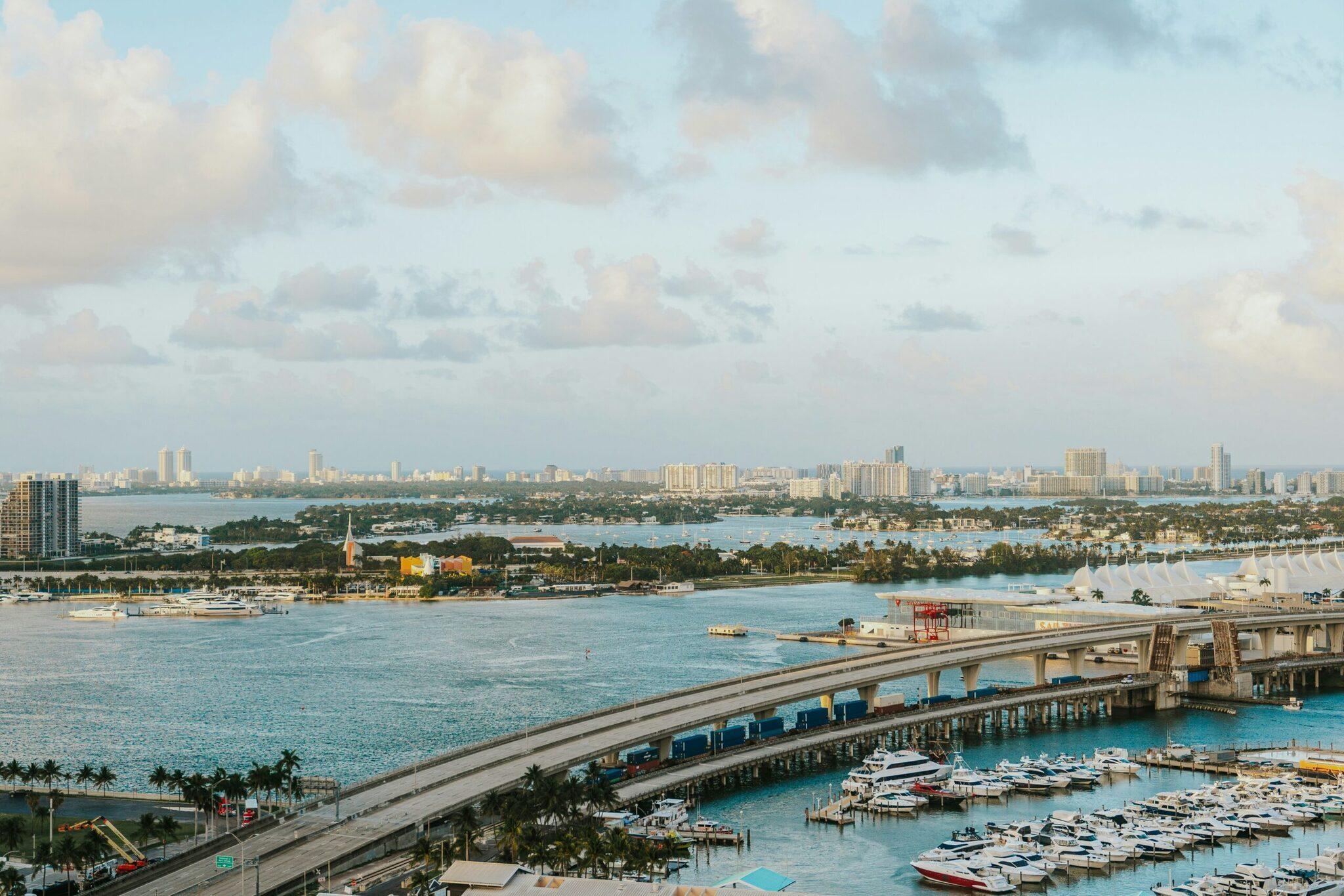 Vue aérienne d’un port maritime tropical avec bateaux amarrés, pont autoroutier et skyline urbaine en arrière-plan