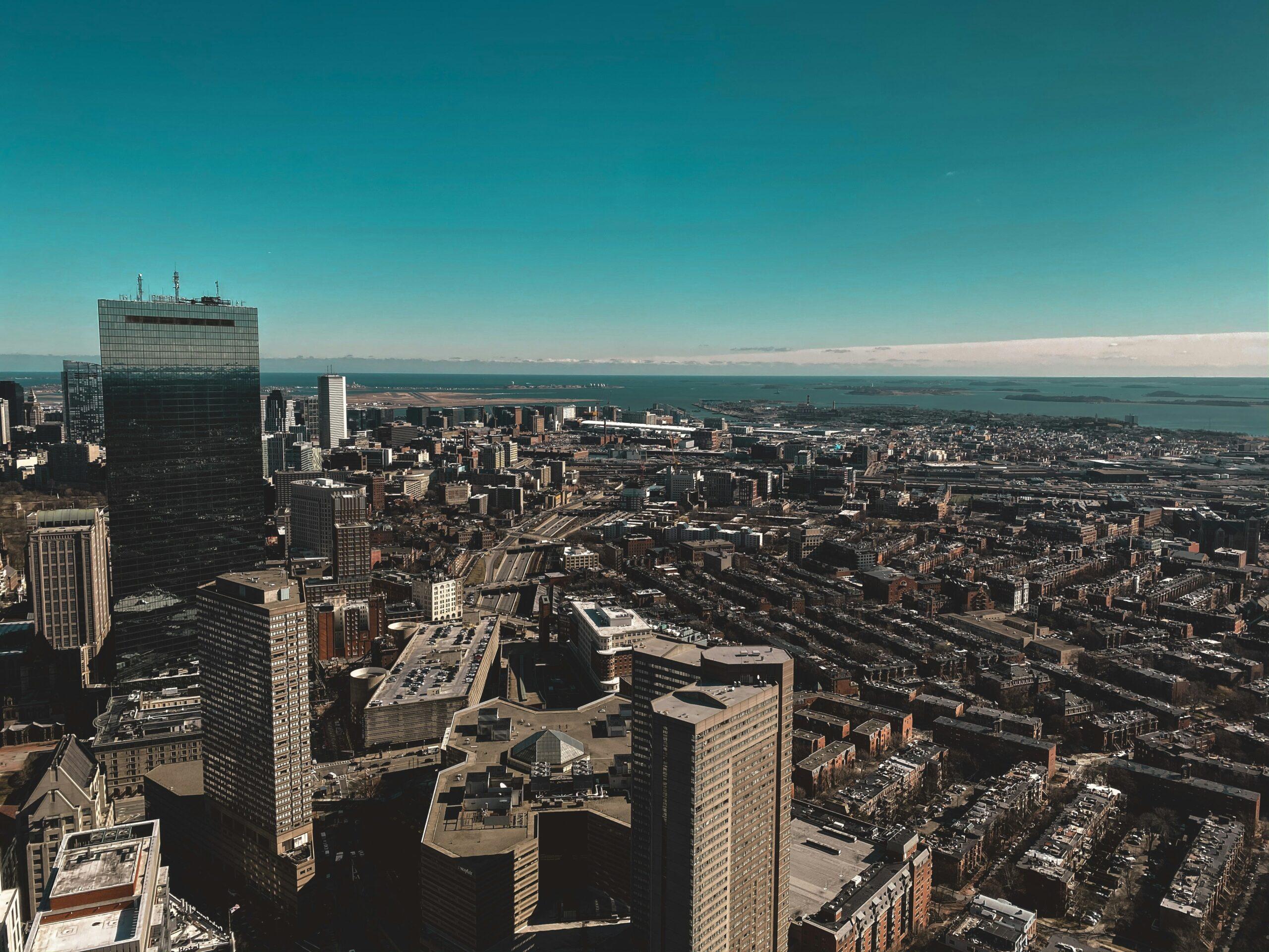 Vue aérienne d’une métropole côtière avec gratte-ciel, immeubles résidentiels et une baie turquoise en arrière-plan