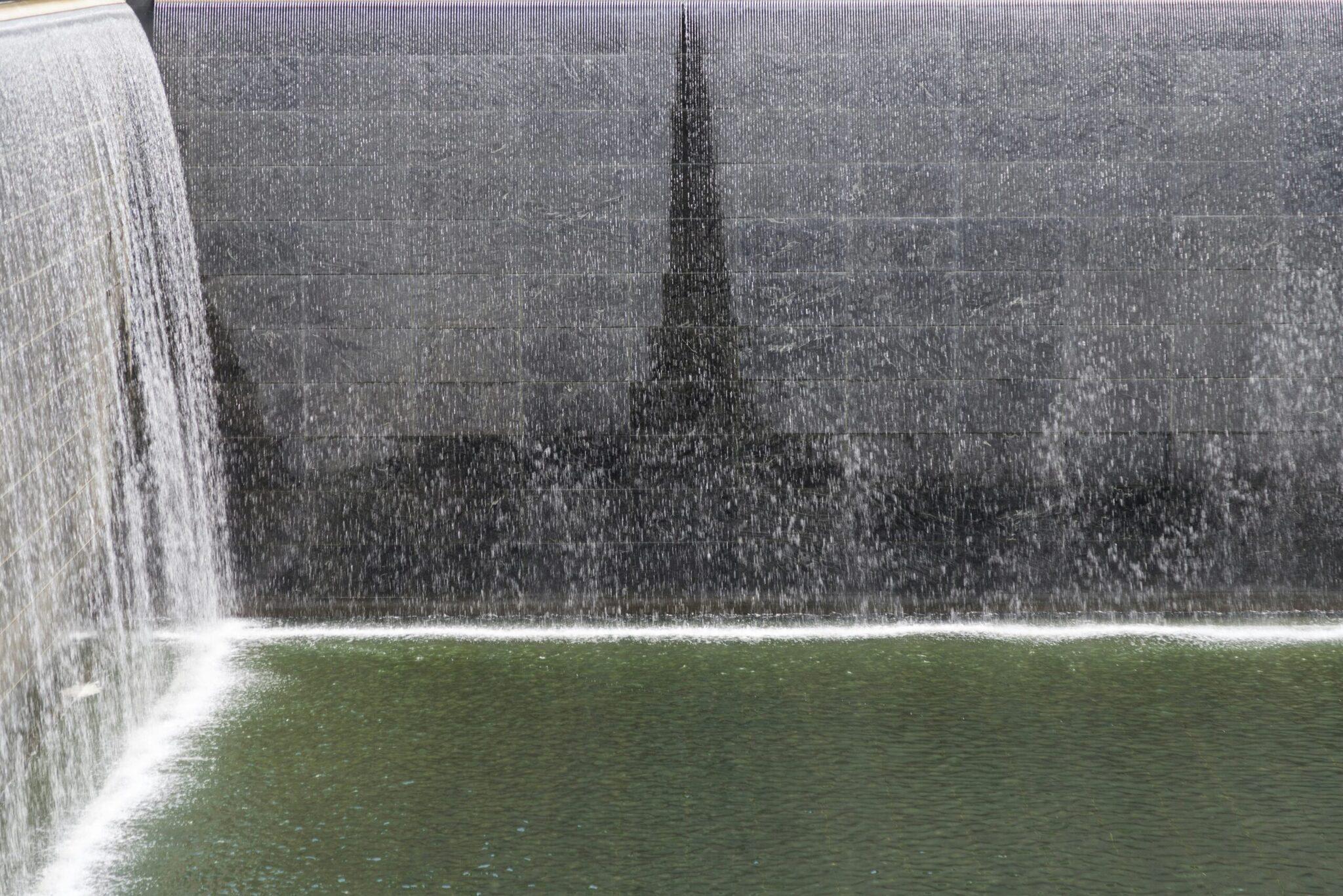 Cascade d’eau monumentale jaillissant d’une structure en béton avec bassin vert en contrebas