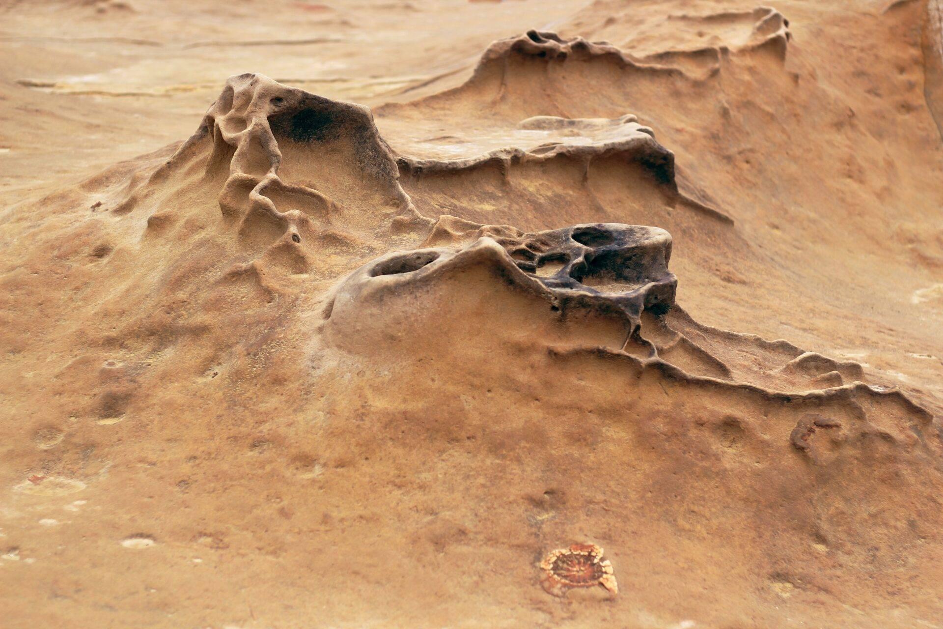 Formations rocheuses érodées et sculptées dans un paysage désertique aride aux teintes ocre et beige