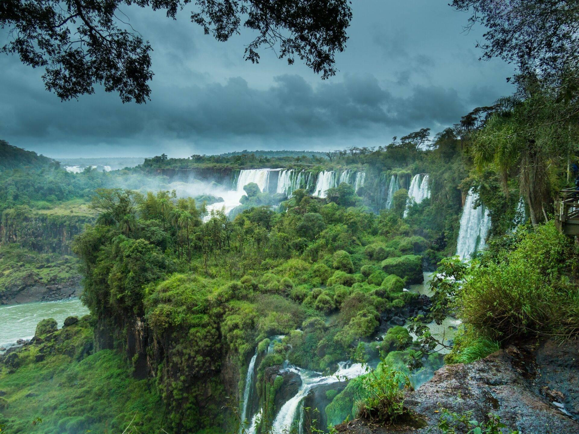 Cascade spectaculaire entourée de jungle dense avec plusieurs chutes d’eau blanc éclatant sous ciel nuageux