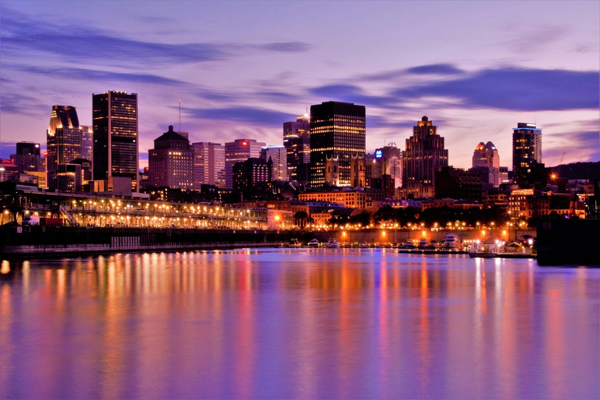 Skyline illuminé d’une métropole nord-américaine au crépuscule, reflété dans les eaux calmes d’un fleuve