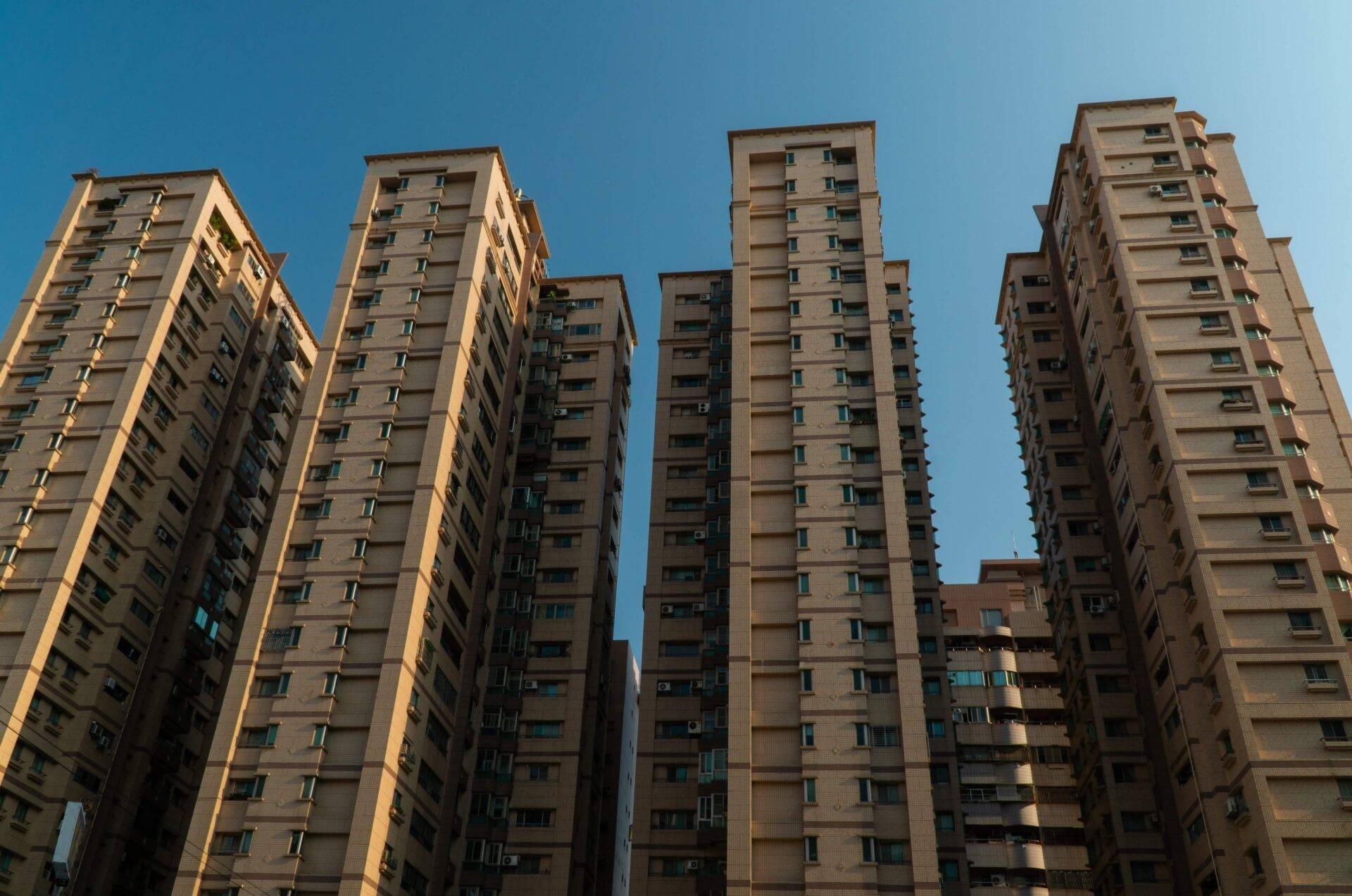 Immeubles résidentiels modernes en béton beige alignés sous un ciel bleu dégagé en zone urbaine