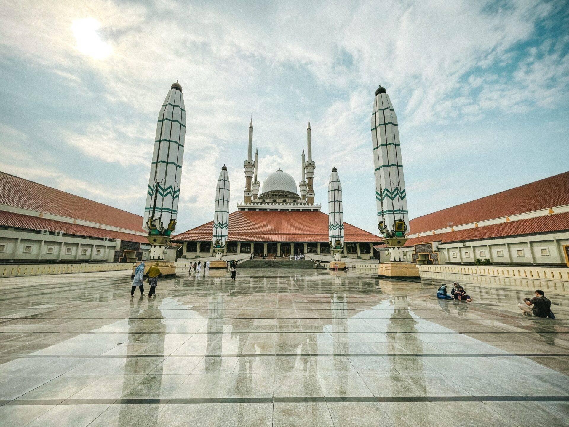 Grande mosquée avec dôme blanc et minarets ornementaux, cour pavée réfléchissante, architecture islamique majestueuse