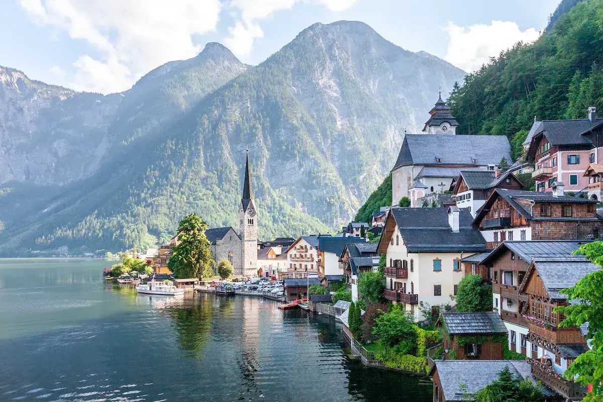 Un petit village alpin au bord d’un lac cristallin, dominé par des montagnes boisées et une église caractéristique