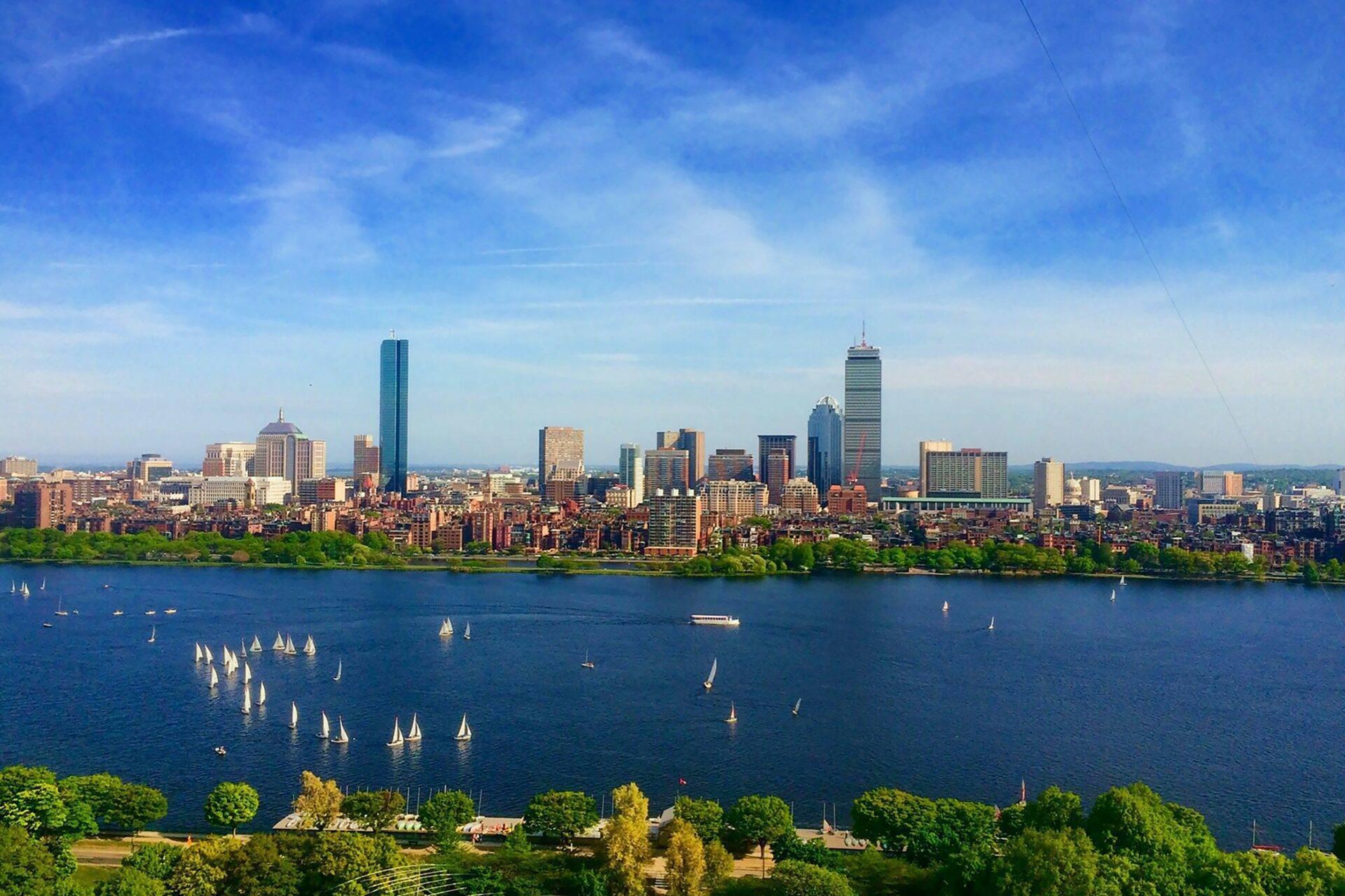 Skyline urbain américain avec gratte-ciel surplombant une baie bleue parsemée de voiliers blancs et de végétation verte