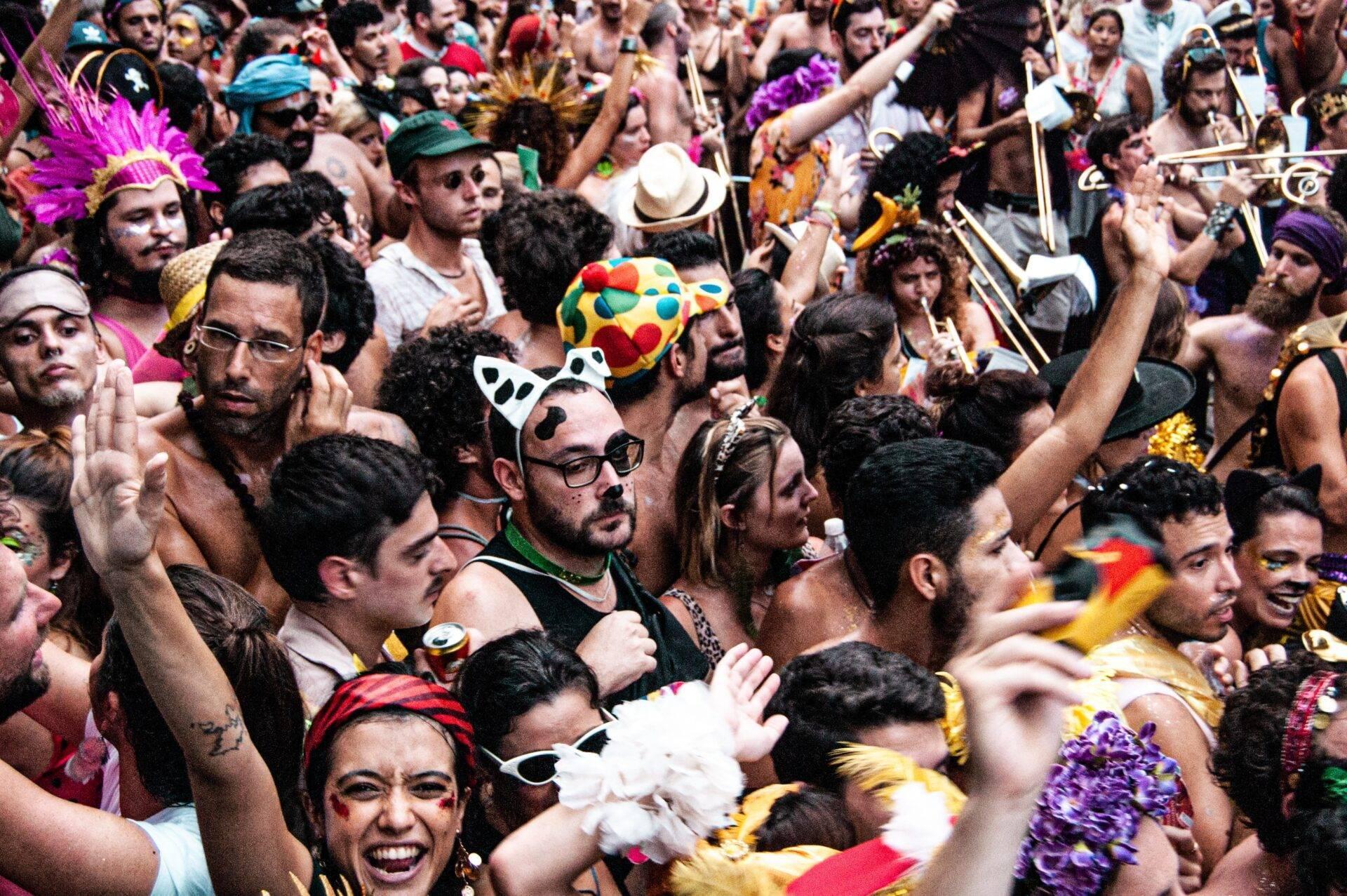 Une foule dense et colorée en costumes de carnaval avec masques, plumes et accessoires festifs