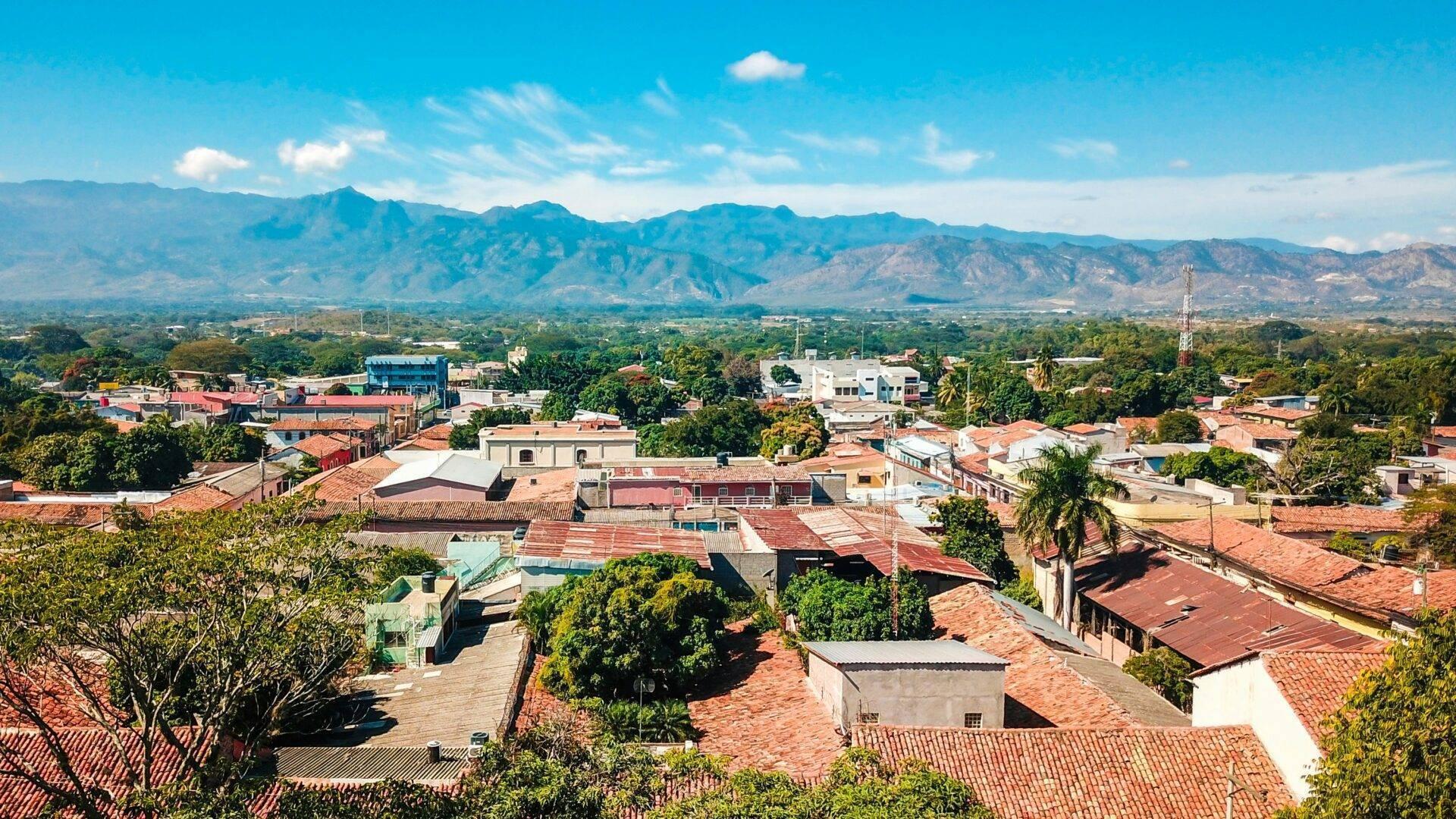 Vue panoramique d’une petite ville coloniale avec montagnes verdoyantes en arrière-plan sous ciel bleu