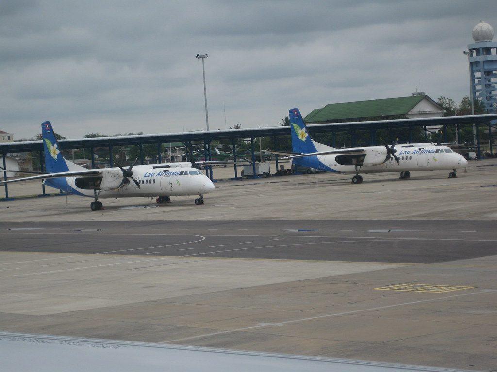 Voyageur consultant son téléphone dans un aéroport, carte d’embarquement à la main